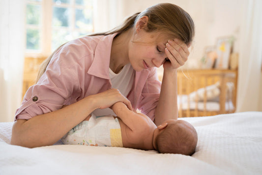 A mother gently interacting with her baby on a bed.
