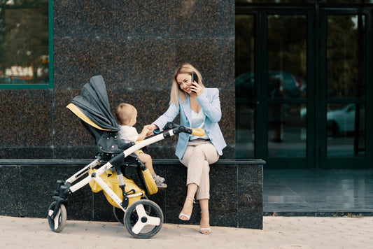A woman sitting on a bench with a baby in a yellow stroller.