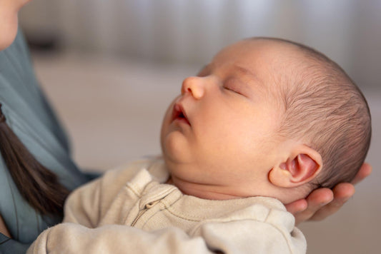 Sleeping newborn baby held in a person's hands.